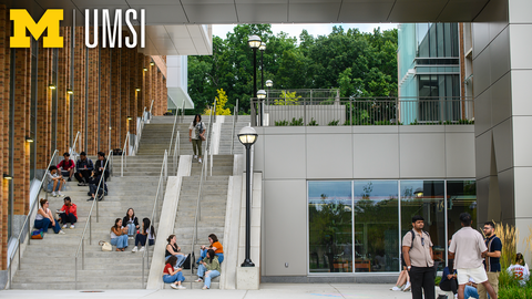 A view of tall stairs alongside a brick academic building, with students lounging on them in small groups