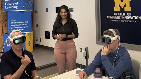 Dhruvi Jagani looks on as two people wear virtual reality headsets