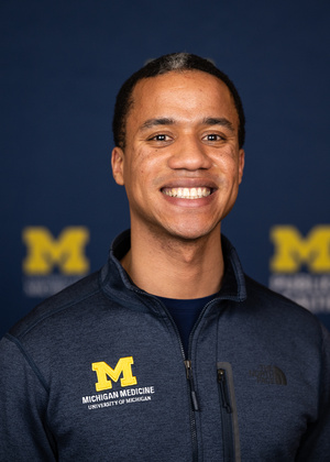 A headshot of Ejike Anusiem wearing a jacket with a Michigan Medicine logo.