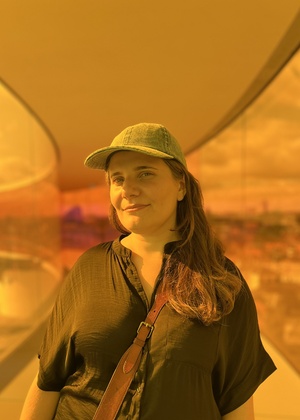 Nazanin Andalibi standing in a long skyway. Everything is tinted orange.