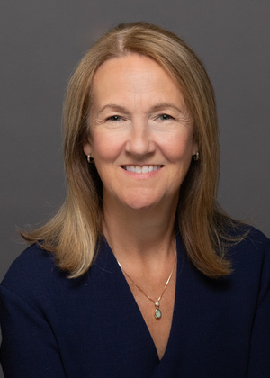 Professional headshot, plain background. Female, medium length light brown hair.