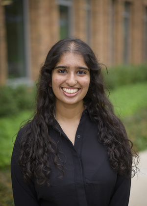 Headshot of Tania Mishra outdoors in a black button-down shirt.