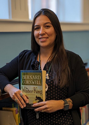 A photo of Briana Kemmerling holding the book "Winter King" by Bernard Cornwell
