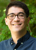 Benjamin Lee, University of Washington, wearing a blue button up shirt, with brown hair and glasses, smiling. 